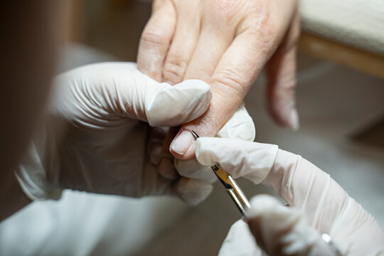 In a beauty salon, a manicurist is trimming a client's cuticles (Stock Photo).