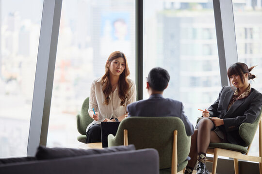 Young businesswomen listening to male manager in team meeting at office
