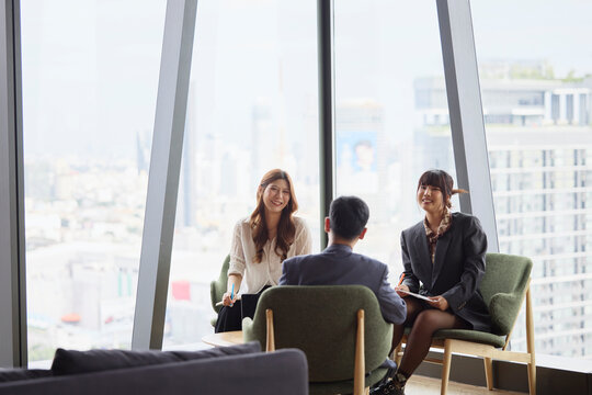 Smiling businesswomen communicating with male manager in team meeting at office