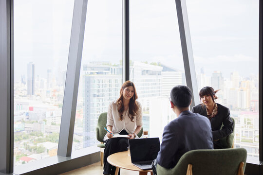 Smiling businesswoman communicating with male and female coworkers at office