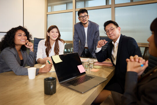 Smiling male and female entrepreneurs sitting around table in meeting room