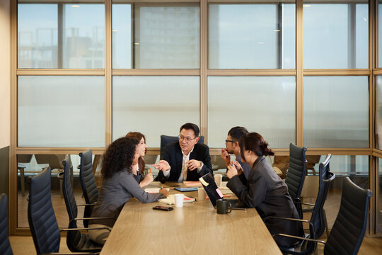 Manager explaining strategies colleagues to sitting around table in meeting room