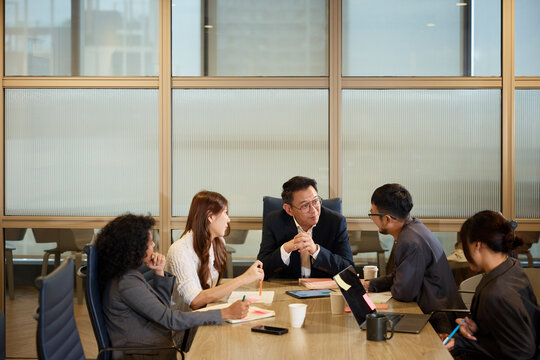 Manager listening colleagues sharing ideas while sitting around table in office