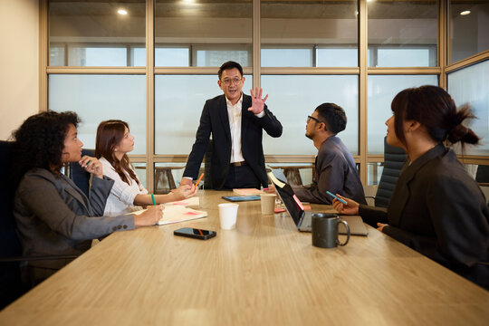 Manager explaining marketing skills to colleagues sitting around table in office