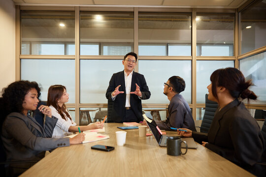Manager discussing marketing skills with team sitting around table in meeting room