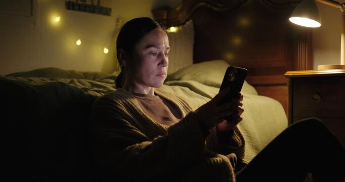 Woman Using a Smartphone in a Dark Bedroom at Night