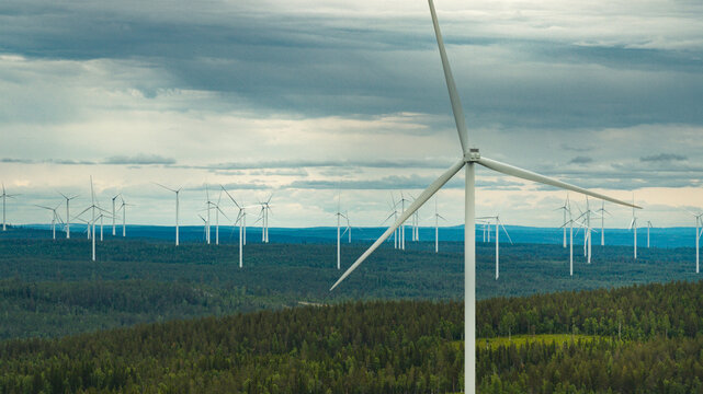 Wind turbines amidst trees against cloudy sky
