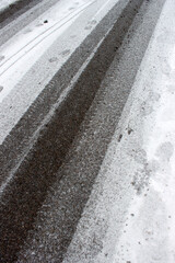 Tire and footprints on thawing asphalt with deicing granules &mdash; ideal for municipal winter services and urban environmental documentation