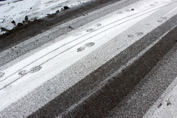 Tire and footprints on melting snow with deicing agent residue &mdash; ideal for municipal winter maintenance and environmental impact documentation