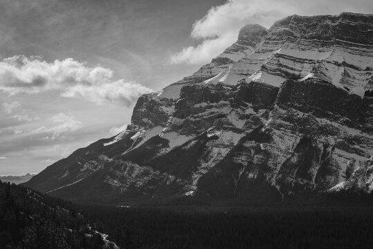 Black and white image of snowcapped mountains against cloud sky