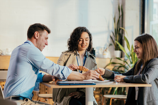 Coworkers sharing croissants during a productive coffee break
