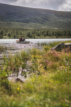 Distant view of people sitting on rowboat in lake