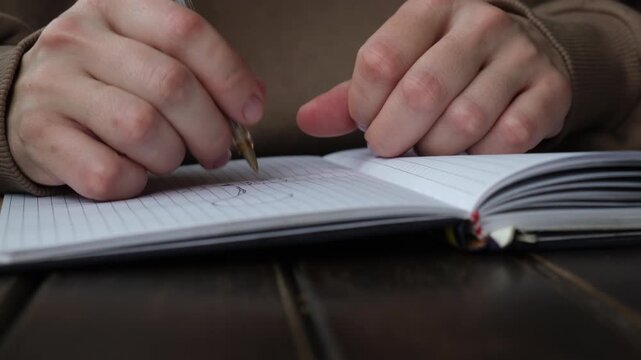 Writer's block, no idea or creative crisis. Hands nervously holding pen over notebook