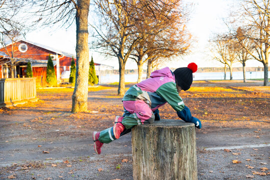 Full length of girl climbing on wooden log in public park