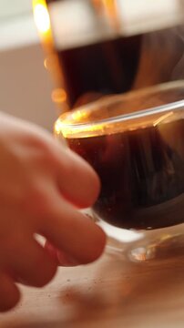 Fresh coffee is poured from a moka pot into a cup in a home kitchen.
