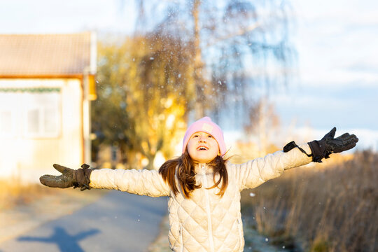 Carefree girl wearing warm clothes enjoying snow with arms outstretched