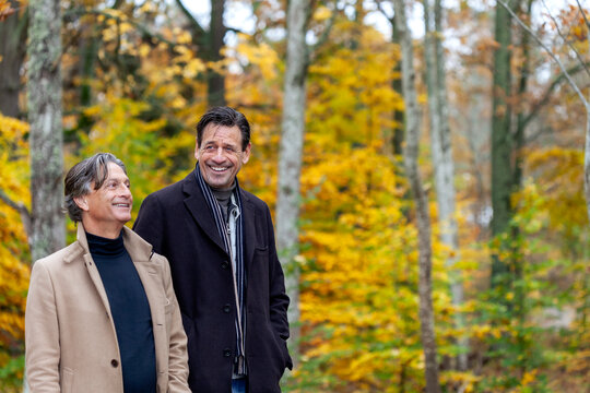 Happy senior men spending leisure time while strolling in autumn forest