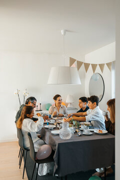 Family eating lunch while sitting around dining table at home
