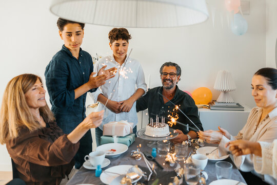 Cheerful family burning sparklers while celebrating birthday at home