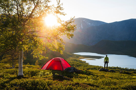 Man looking at lake while camping on hill at sunny day