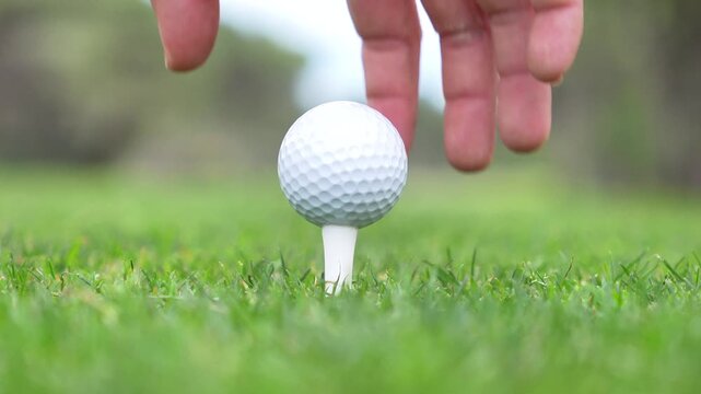 A person is holding a golf ball and preparing to hit it with a golf club. Concept of focus and determination, as the person is getting ready to make a shot on the golf course