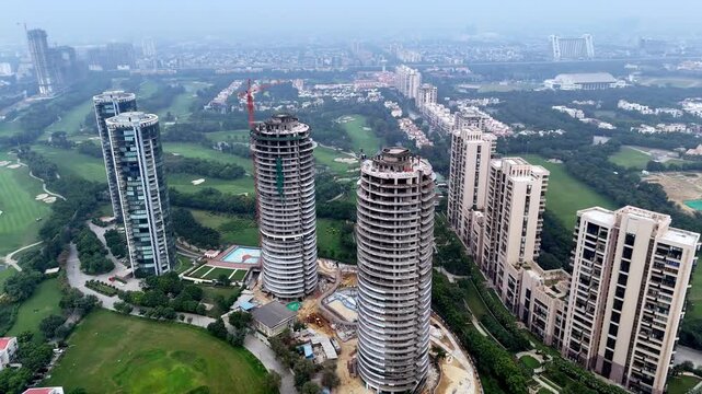 Aerial footage of Sun Court towers in Jaypee Greens, where luxury high-rises overlook golf greens and tree-lined avenues, fading into the hazy skyline of Greater Noida.