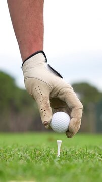 A man is holding a golf ball and a golf club, preparing to hit the ball. Concept of focus and determination, as the man is getting ready to make a shot on the golf course