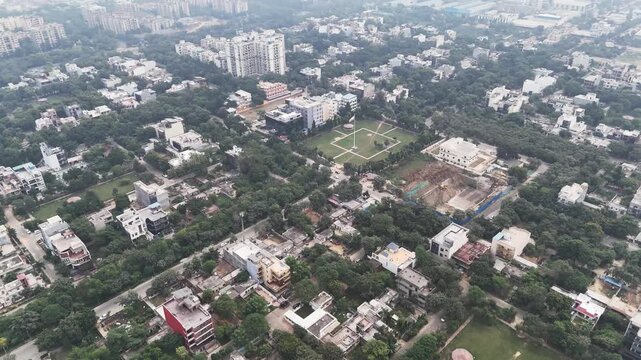 High-angle aerial video of compact housing clusters and greenery intersected by a main road, with atmospheric haze in the background revealing the impact of air pollution in the NCR region.