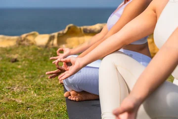 Fotobehang Lotusbloem Women meditating outdoors in lotus position by ocean  © unai