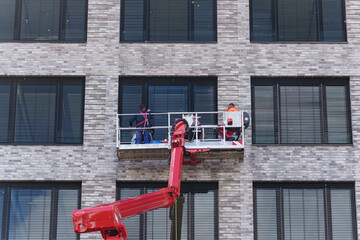 Construction workers using lift platform to service modern brick office building facade © Aleksandr Fedosov