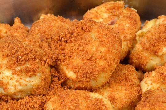 A detailed close up shot of several traditional potato plum dumplings coated in golden toasted breadcrumbs inside a metal bowl