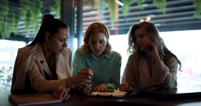 Businesswomen collaborating over coffee and discussing strategies in modern cafe setting during early afternoon hours