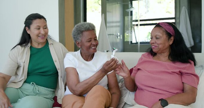 African American women seeing center woman handing face roller leading right woman trying neck home