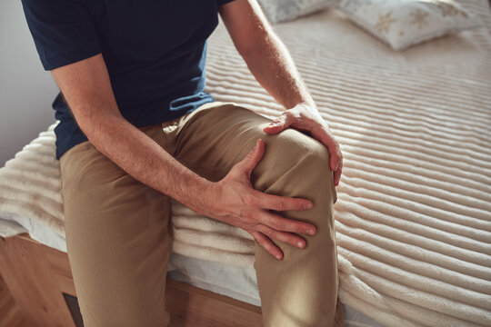 Man at home holding painful injured knee.