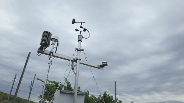 Weather station with cup anemometer, wind vane, thermometer and humidity sensor on a vineyard. Smart farming technology, measuring meteorological conditions. Air quality and climate monitoring.