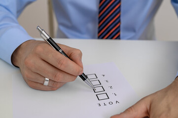 A man casting his vote during an election, holding a ballot paper