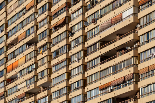 Warm toned Spanish apartment facade packed with balconies in Spain creating dense urban housing rhythm and repeating abstract residential texture