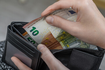A woman takes money out of her wallet and pays for her purchases in cash, euro