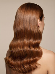 Naklejka premium Wavy brown hair shines with soft curls in a simple background