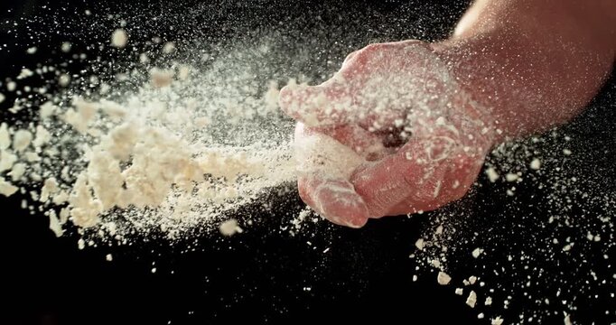 Super slow motion, 1000 fps. Close-up of baker&rsquo;s hand tossing flour over prepared risen dough on wooden table. Cinematic baking concept, artisan bread preparation and texture detail.