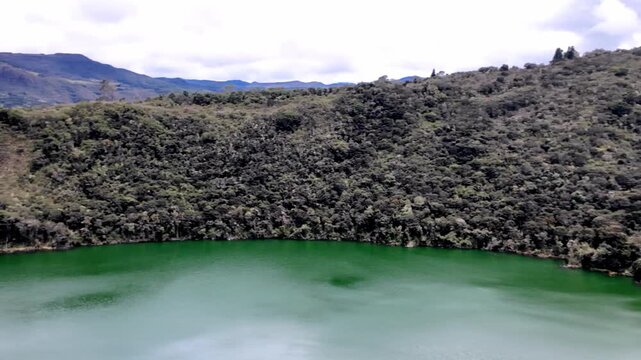 Expansive Panning View of the Sacred Laguna de Guatavita, Colombia, the Legendary Site of El Dorado, Nestled Among Lush Green High-Altitude Mountains.
