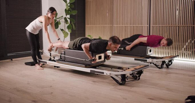 Participants engage in a Pilates workout with a trainer, emphasizing strength and flexibility. The session takes place in a stylish studio, featuring modern equipment and a welcoming atmosphere