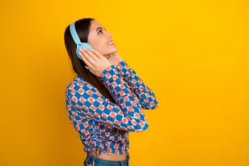 Fotobehang Onderzeeër Young woman wearing blue headphones listening to music against a bright yellow background in a stylish casual fashion photo  © deagreez