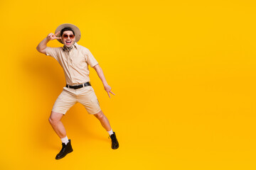 Fototapeta premium Happy traveler in summer safari outfit poses joyfully against a bright yellow background
