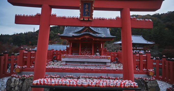 Steady cam movement away from ancient Japanese shrine with scattered little daruma dolls - wide shot