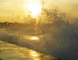 a powerful moment of waves crashing against a shoreline during sunset.