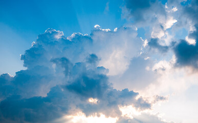 Dramatic clouds with sun rays breaking through blue sky
