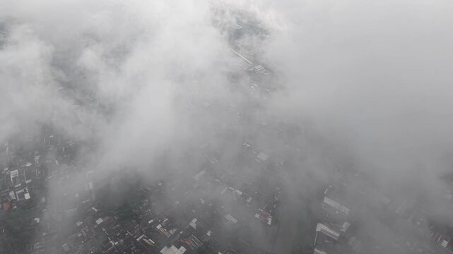 Aerial View Of Foggy Town Below With Clouds Easing Over The Landscape