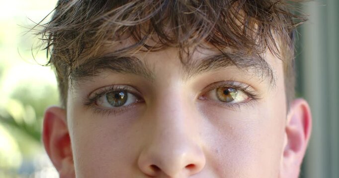 Teenage male blinking and refocusing eyes toward camera near window, reacting to daylight to focus