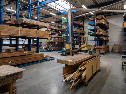 Large industrial timber warehouse featuring extensive racking system, stacked wood materials, and forklift for materials handling operations